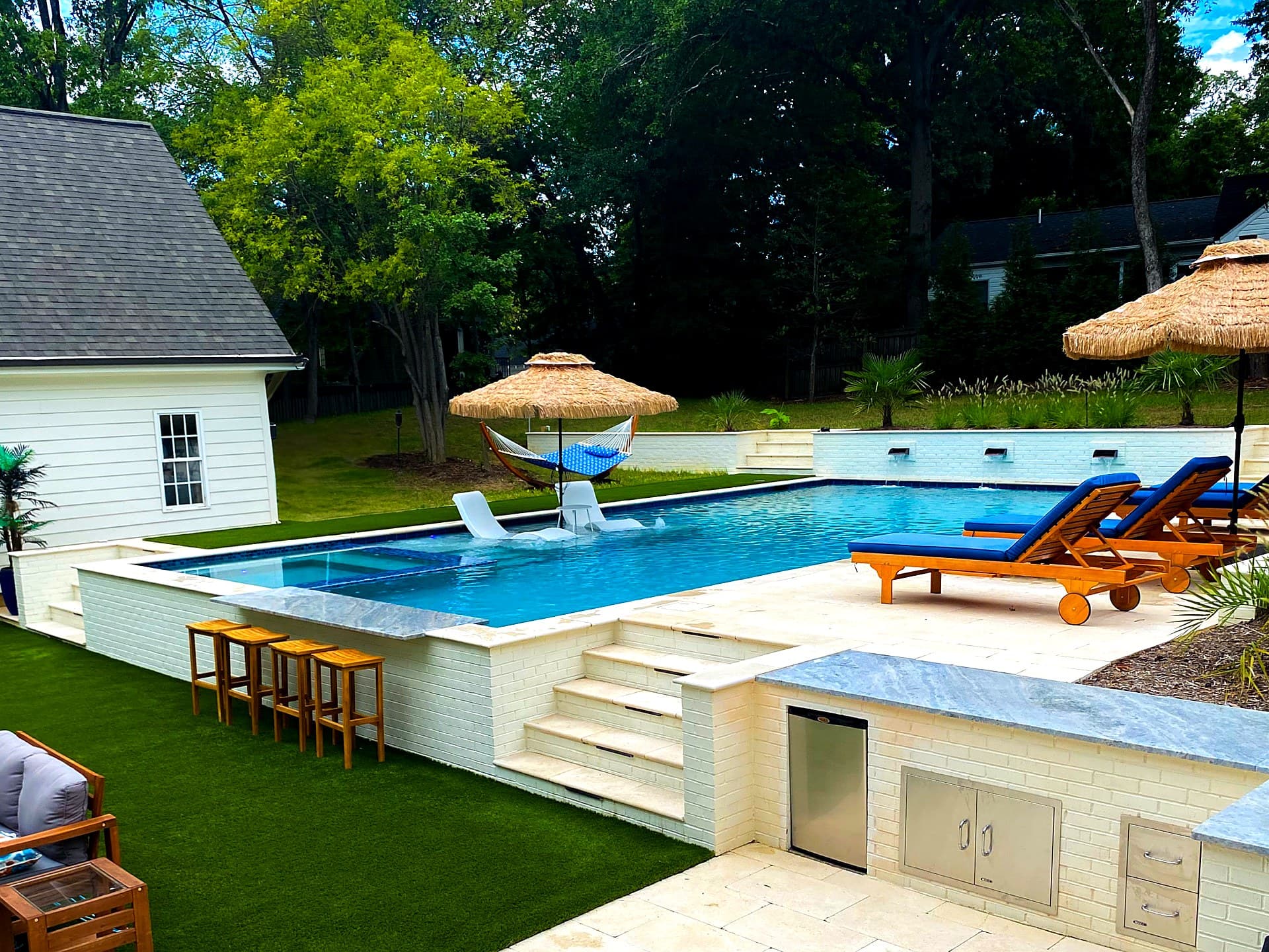 Luxury geometric pool with swim-up bar, tanning ledge, and outdoor kitchen in Charlotte NC