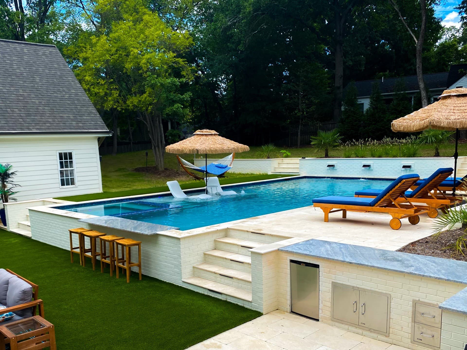 Luxury resort pool with swim-up bar and outdoor kitchen by Blue Waters Construction